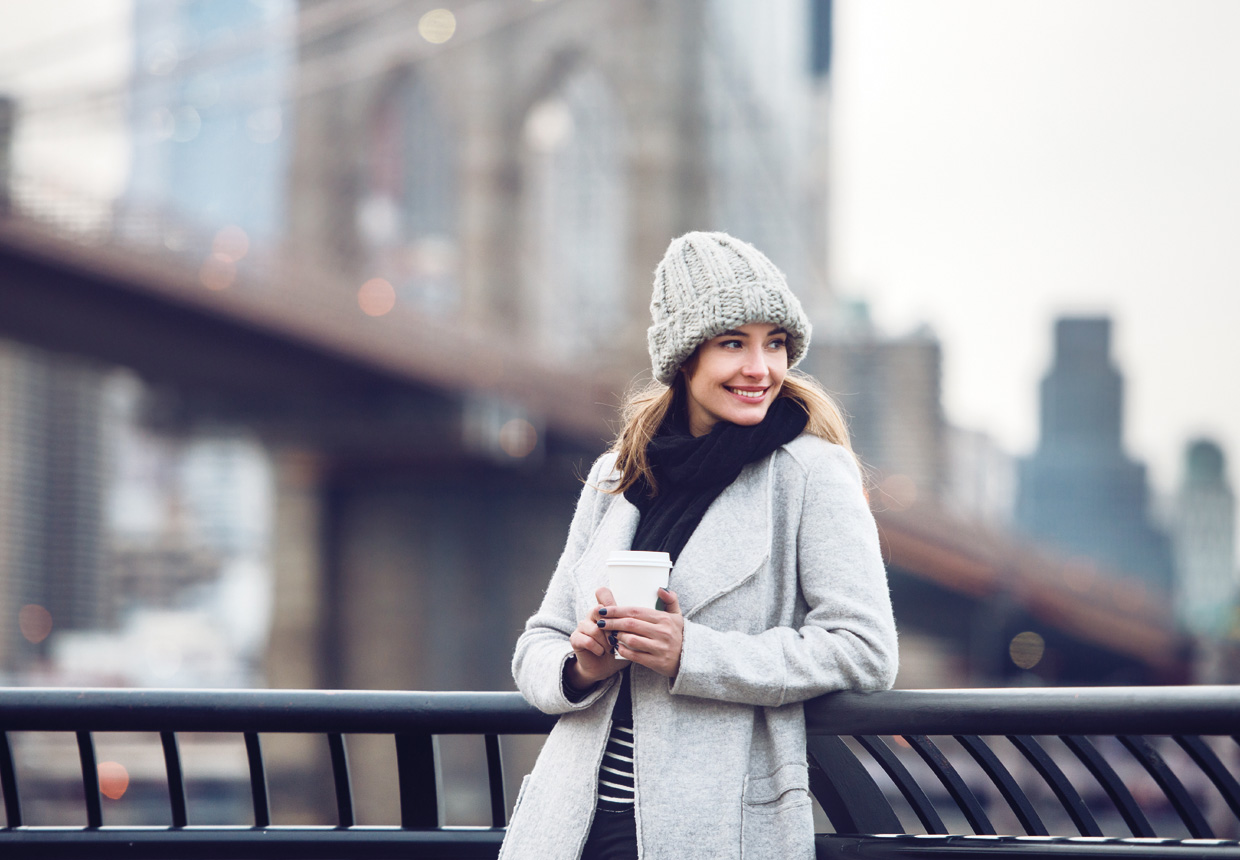 Woman with coffee near the Brooklyn Bridge in winter