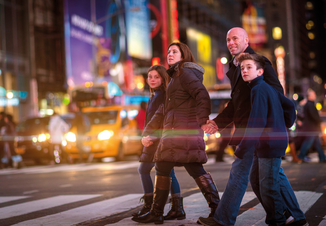 Family crossing a street in Times Square at night