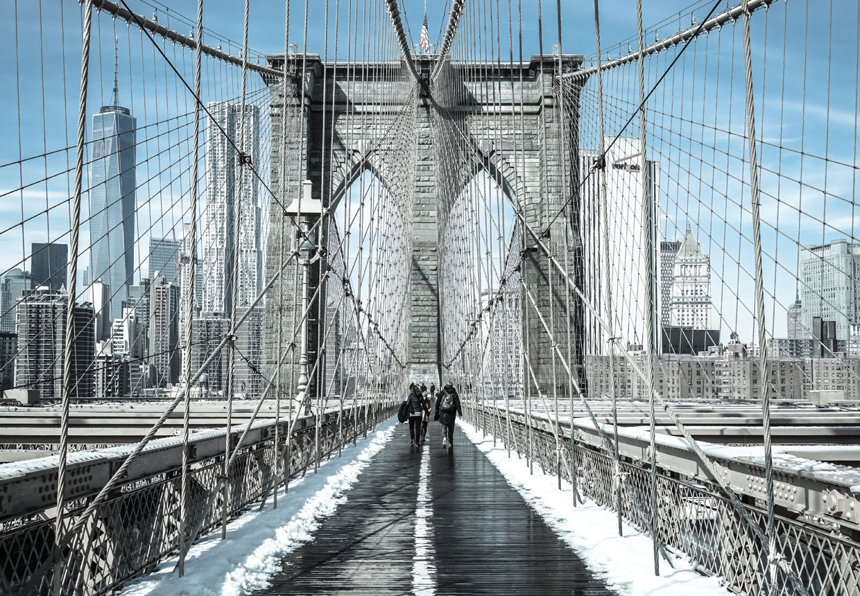 Snow-covered Brooklyn Bridge walkway with Manhattan skyline