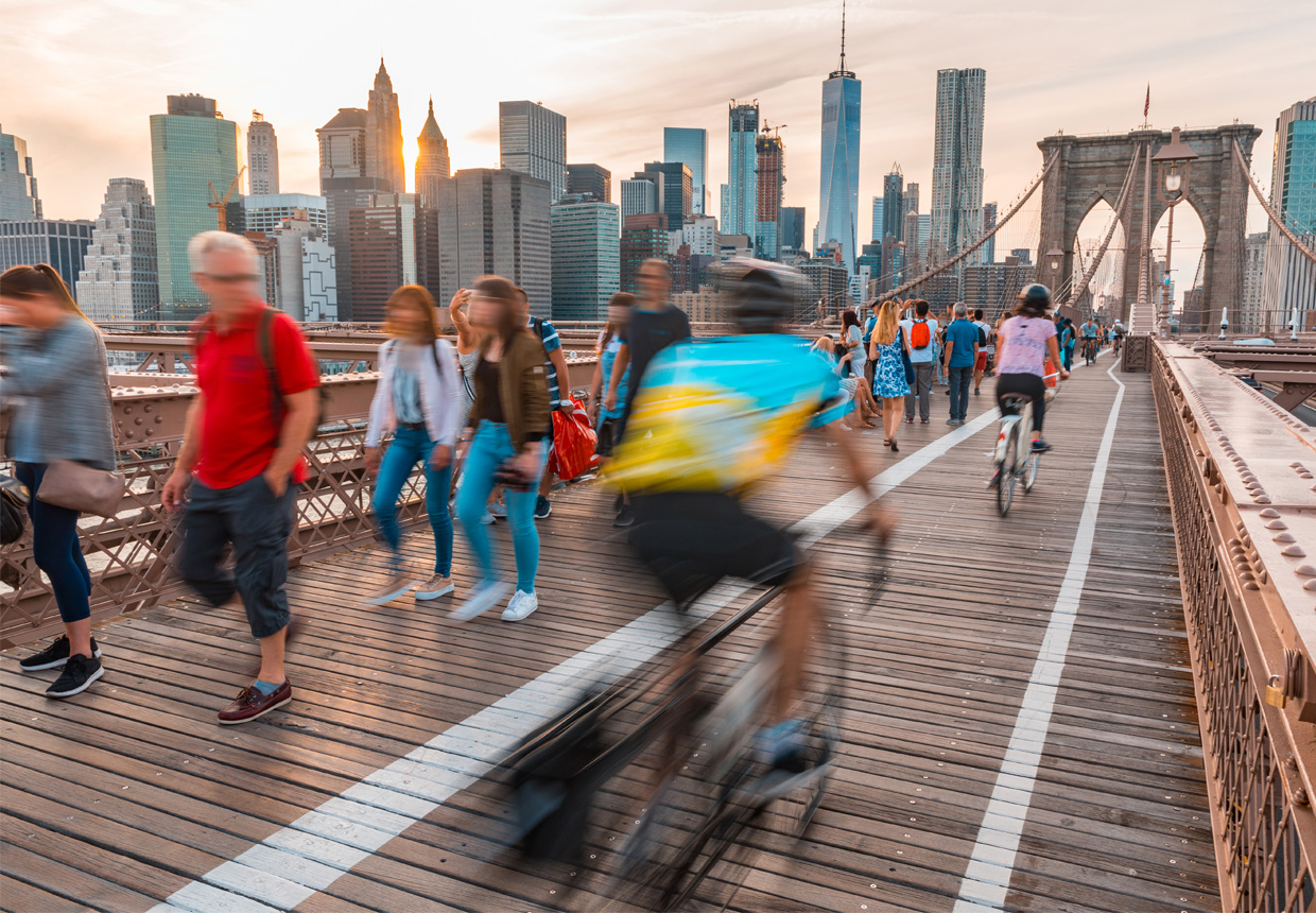 Pedestrians and cyclists on Brooklyn Bridge at sunset