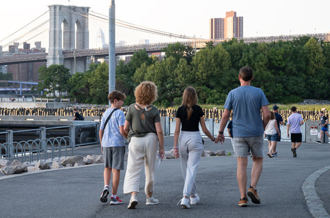 Family walking along the waterfront with Brooklyn Bridge in the background