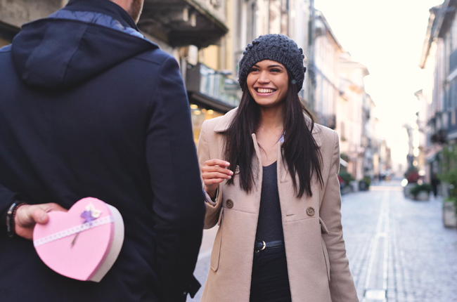 Man surprising woman with a heart-shaped gift box
