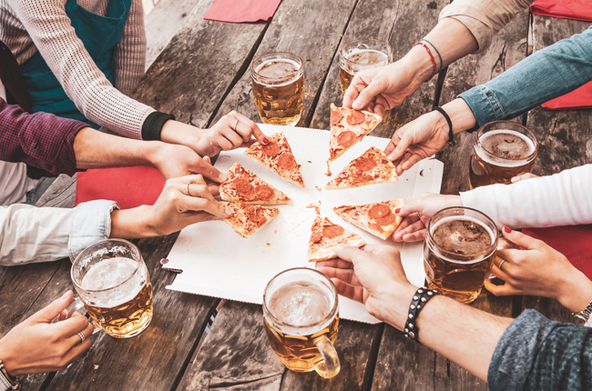 Friends sharing pizza and beer outdoors