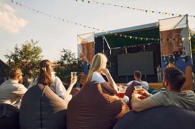 Friends watching an outdoor movie screening with drinks