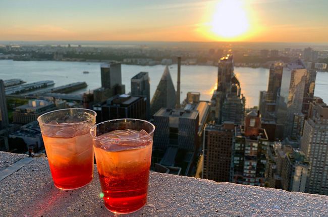 Cocktails at a rooftop bar overlooking the NYC skyline at sunset