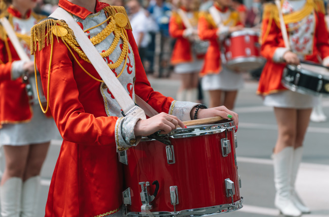 Marching band drummers in red uniforms at a parade