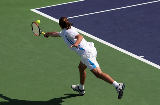 Tennis player reaching for a shot on a hard court
